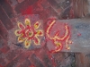 A droite, signe Om Hindou dessiné au sol devant une maison